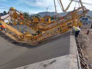 Large equipment and workers constructing a cement ditch